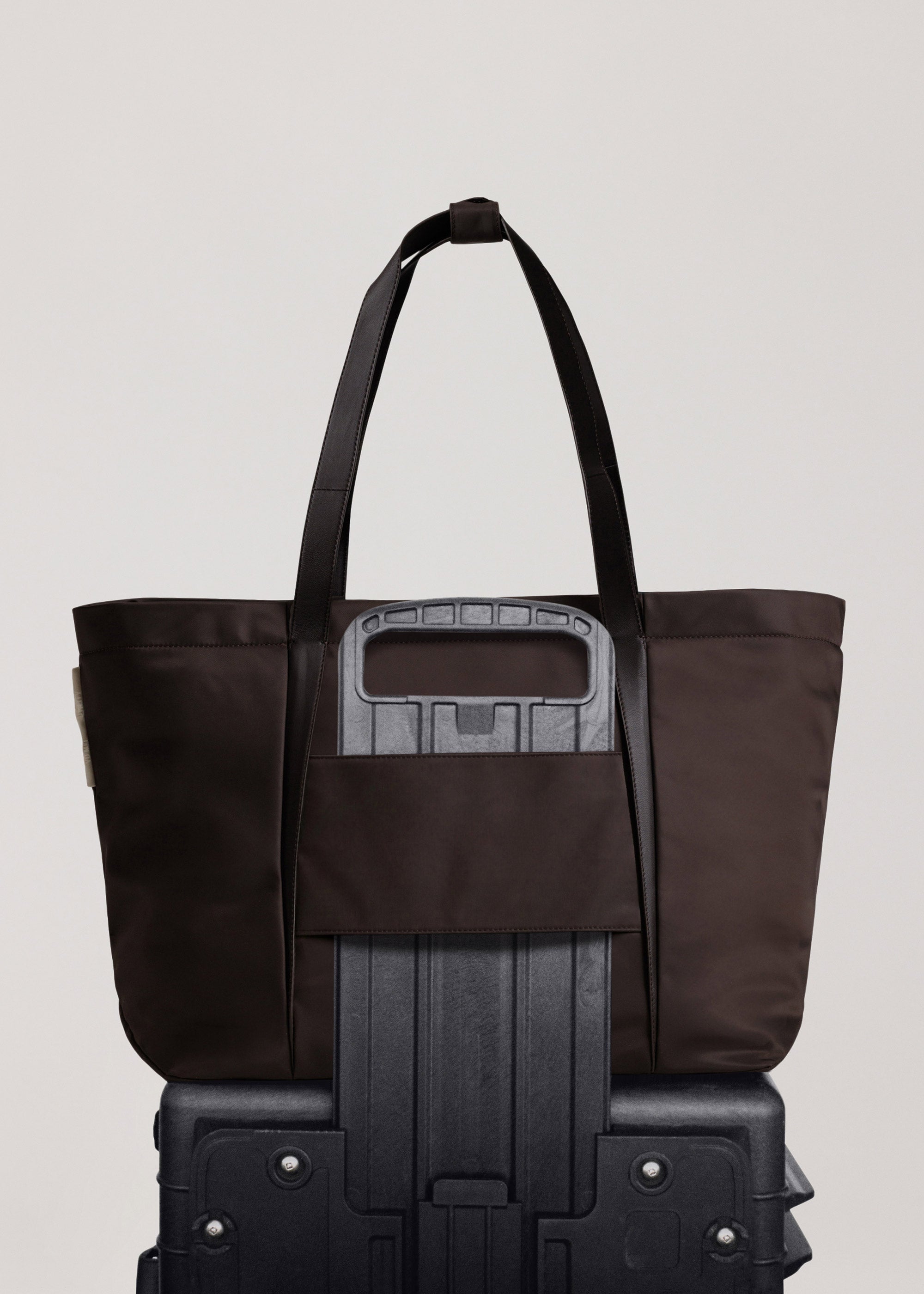 Landscape Tote in ECONYL® regenerated nylon showing travel sleeve over suitcase handle