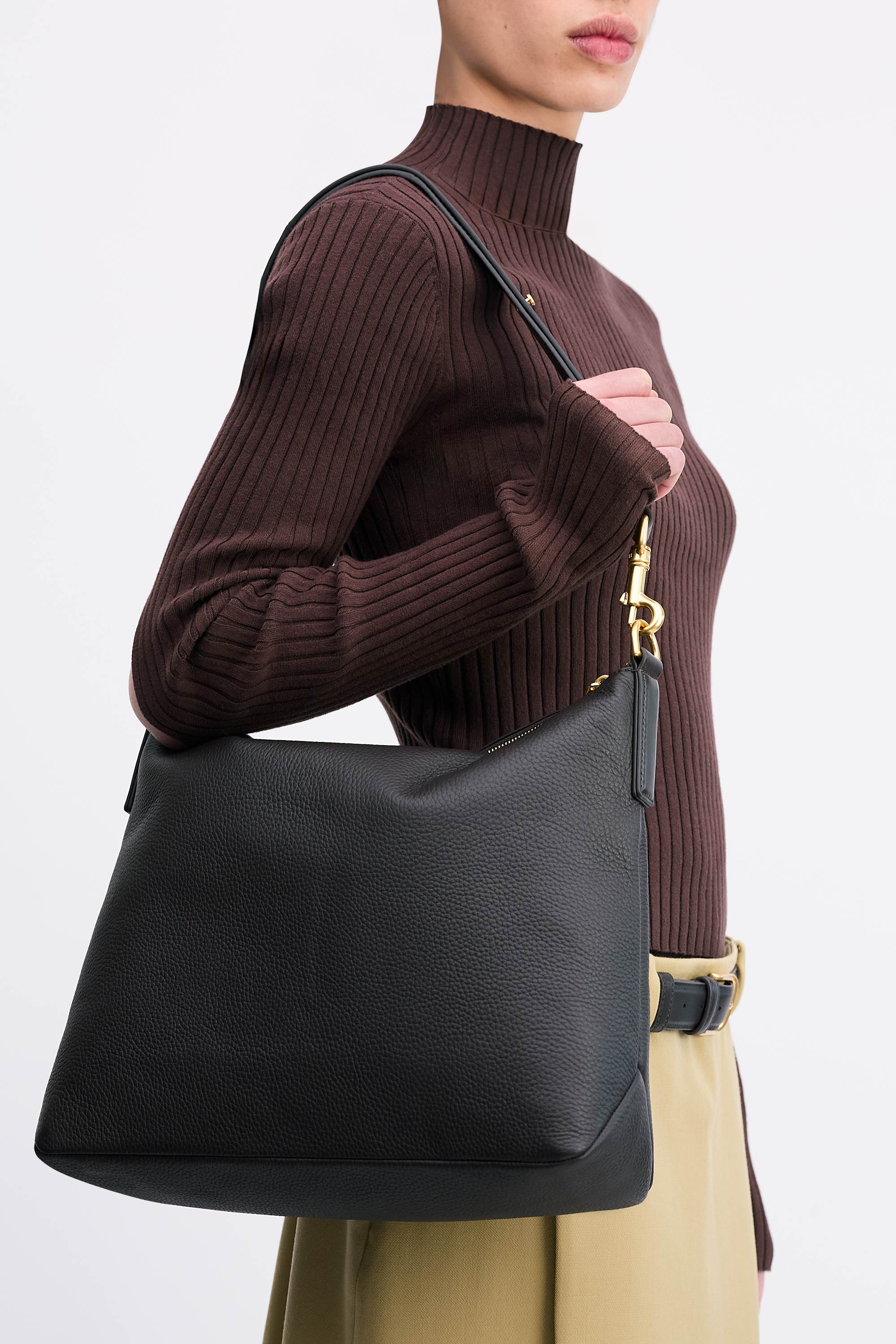Yu Mei Braidy Bag in Black deer nappa worn on shoulder of model wearing brown top and tan skirt