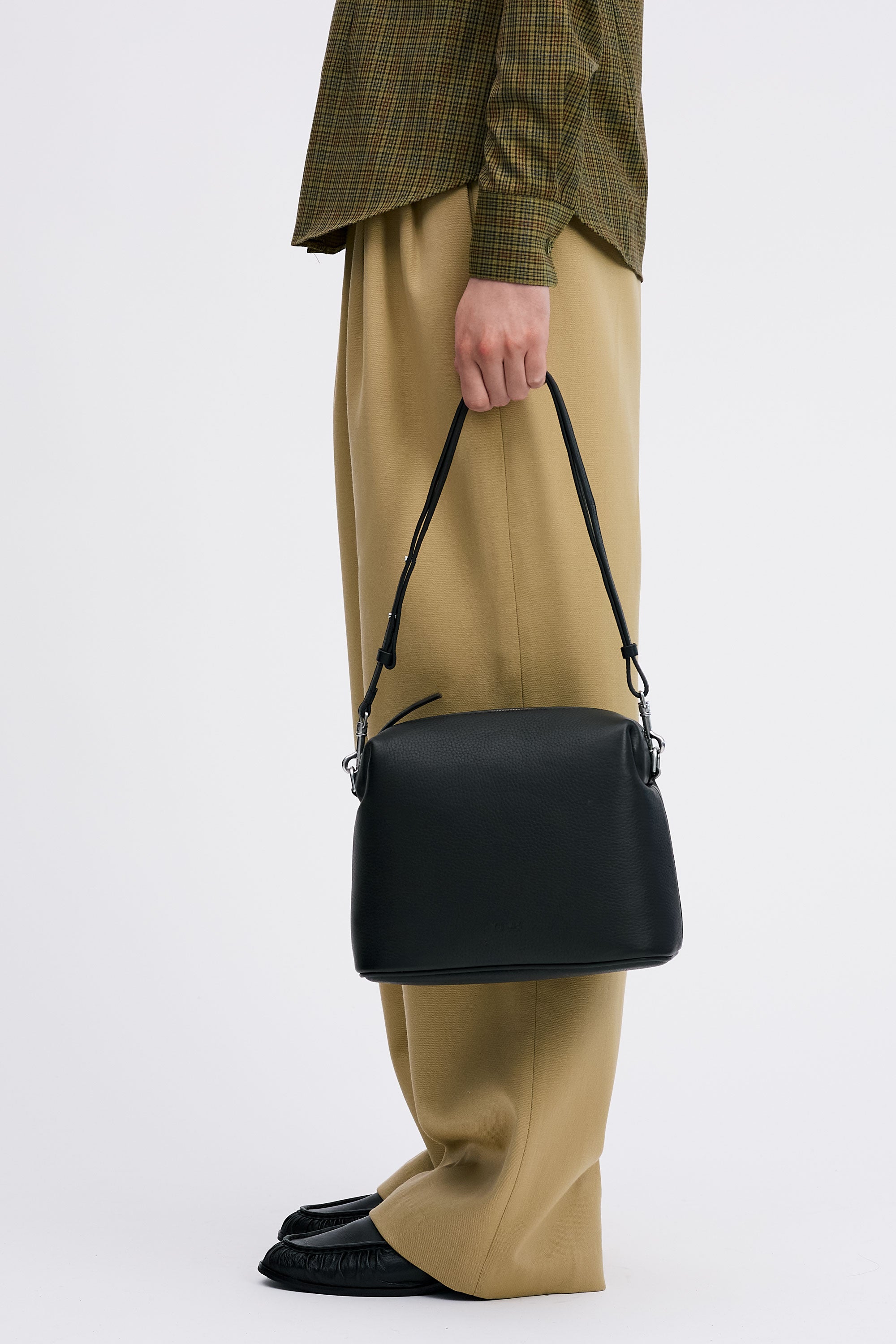Ch'lita Bag in Black Deer Nappa in model's hand wearing check shirt and tan pants