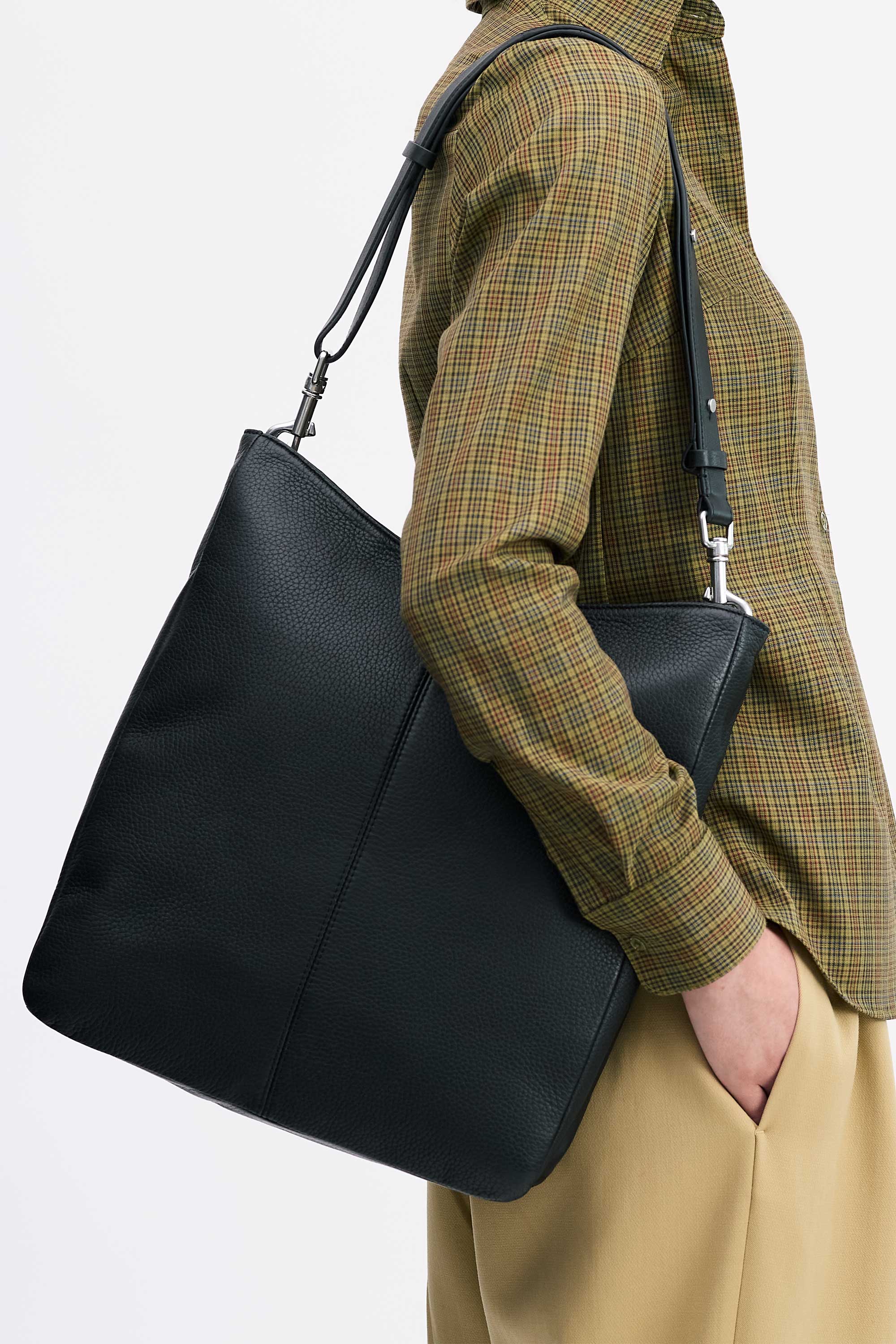 Model wearing the Jane Bag in Black deer nappa on shoulder with check shirt and tan pants