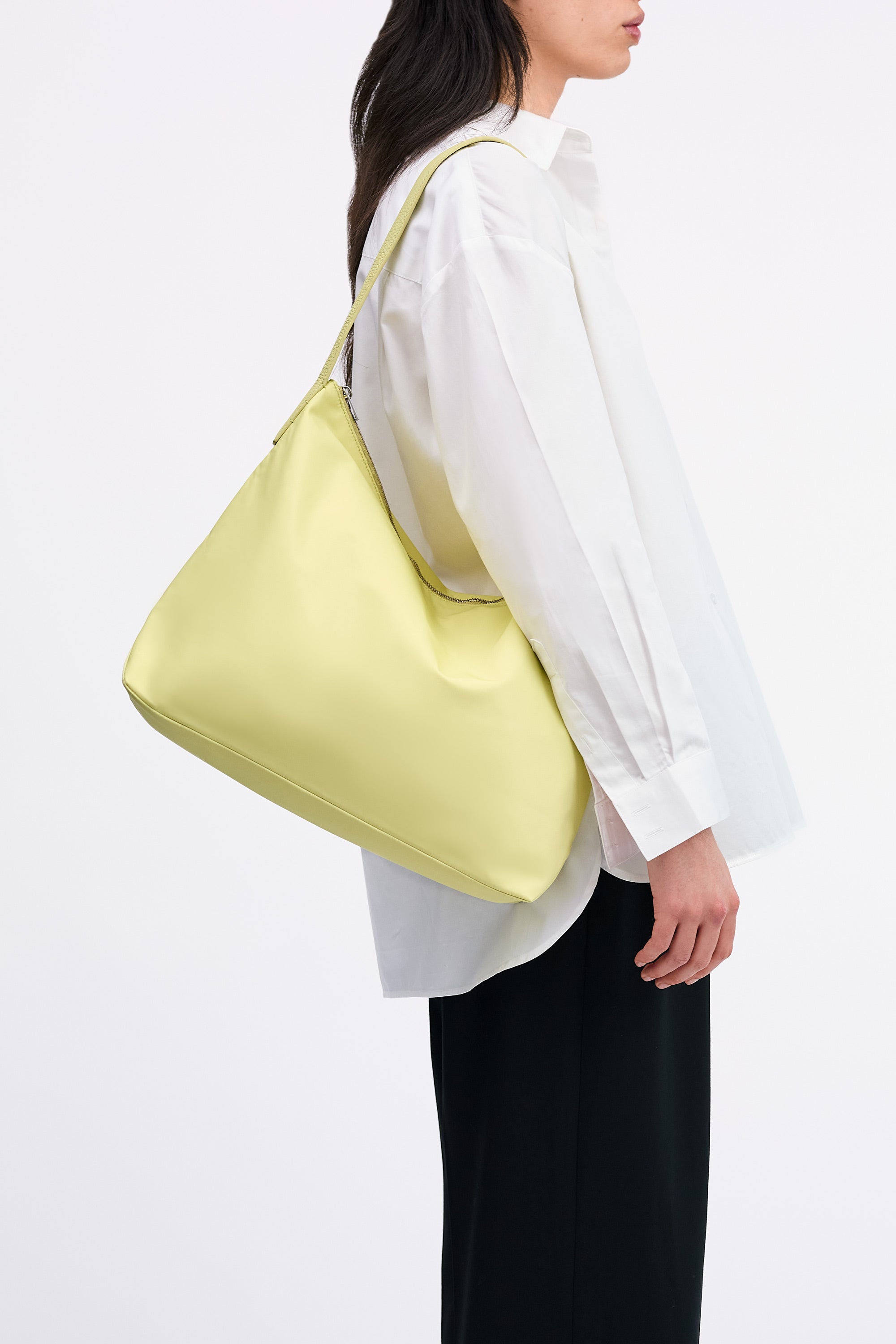 Model wearing the Medium UTILITY Braidy Bag in Half Green nylon on shoulder wearing white shirt and black trousers