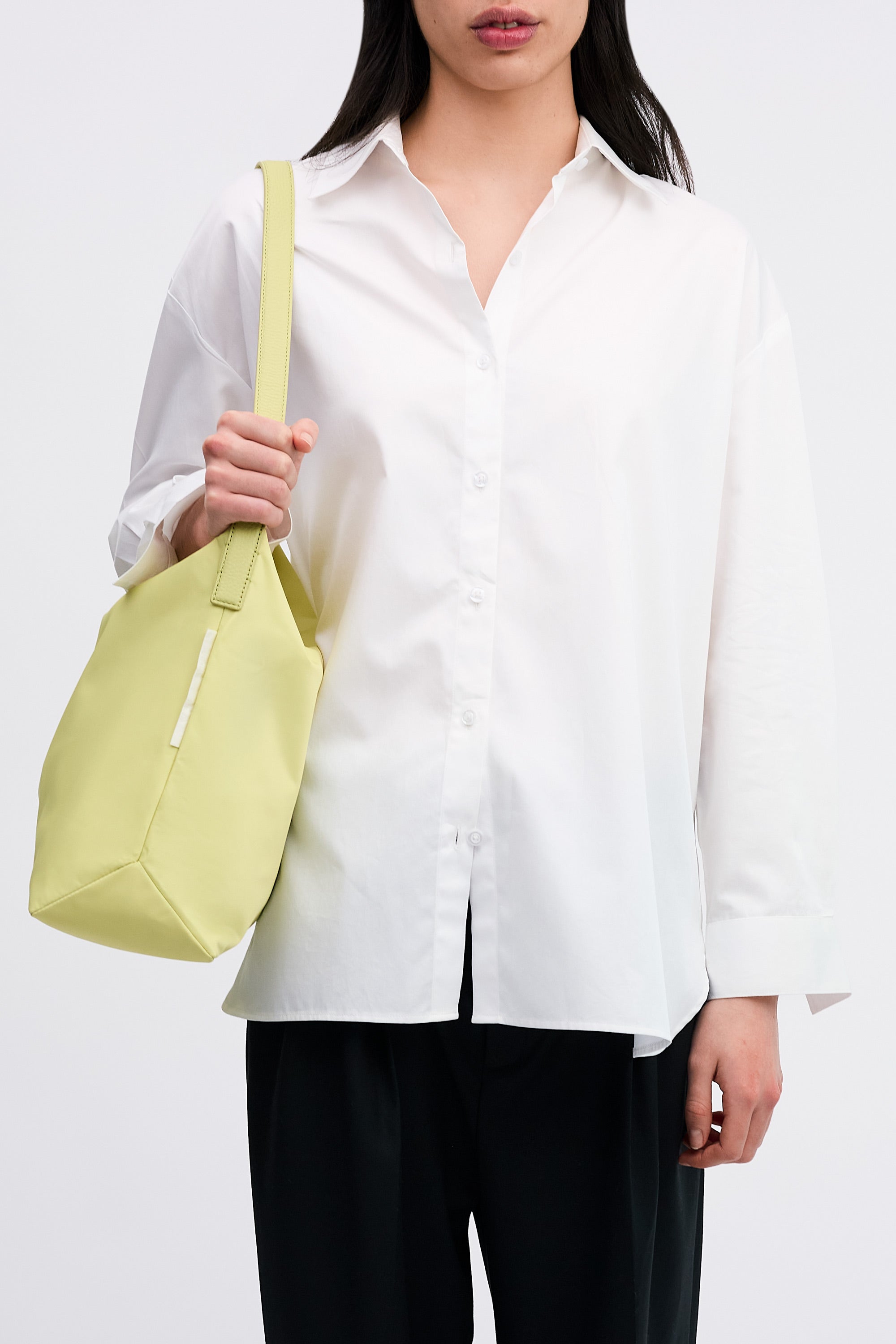 Model wearing the Medium UTILITY Braidy Bag in Half Green nylon on shoulder wearing white shirt and black trousers front view