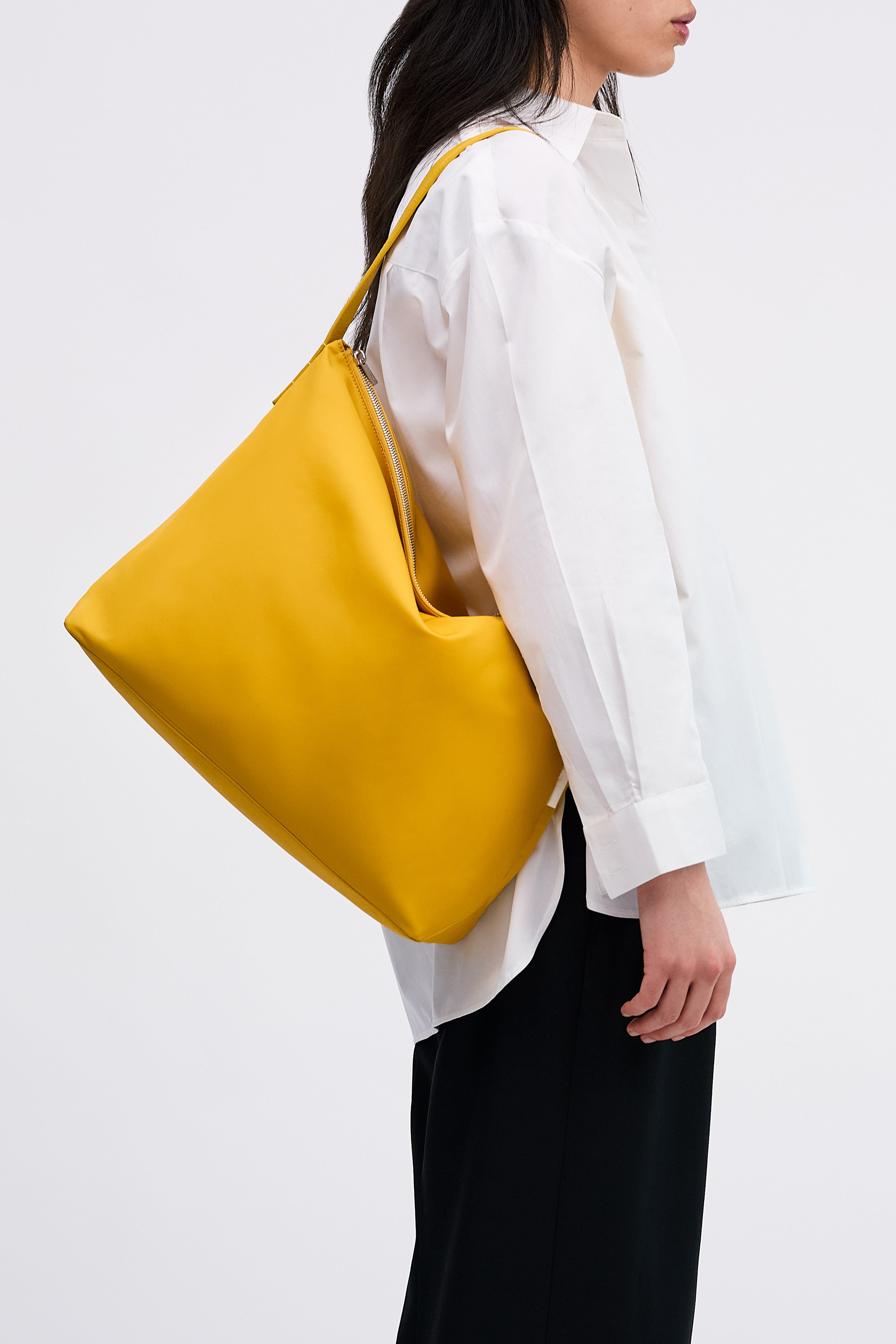 Model wearing the Medium UTILITY Braidy Bag in Honey nylon on shoulder wearing white shirt and black trousers
