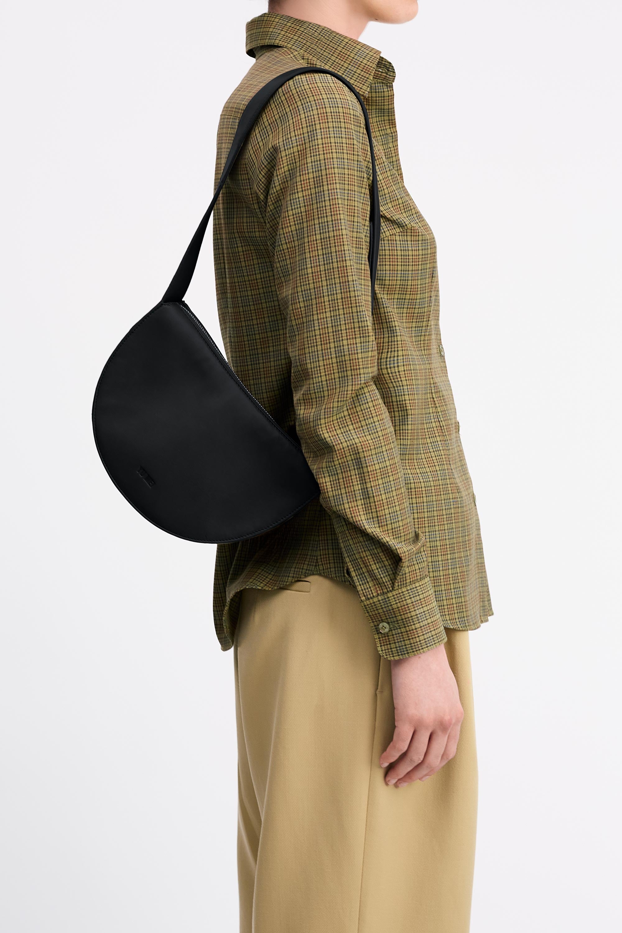 Mini Antonia Bag in Black Lambskin worn on shoulder on model wearing check shirt and tan pants