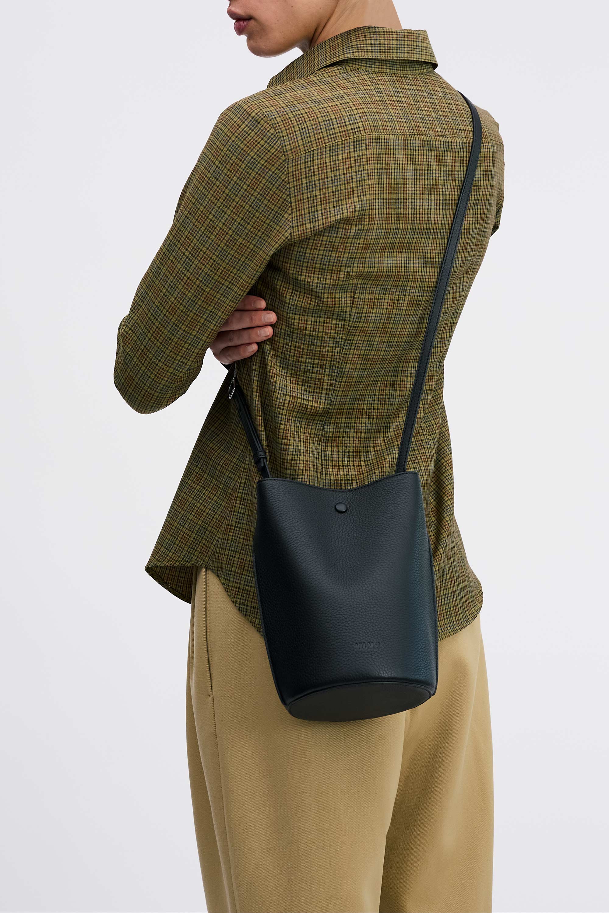 Phoebe Bucket in Black Deer Nappa worn cross-body on model wearing check shirt and tan pants