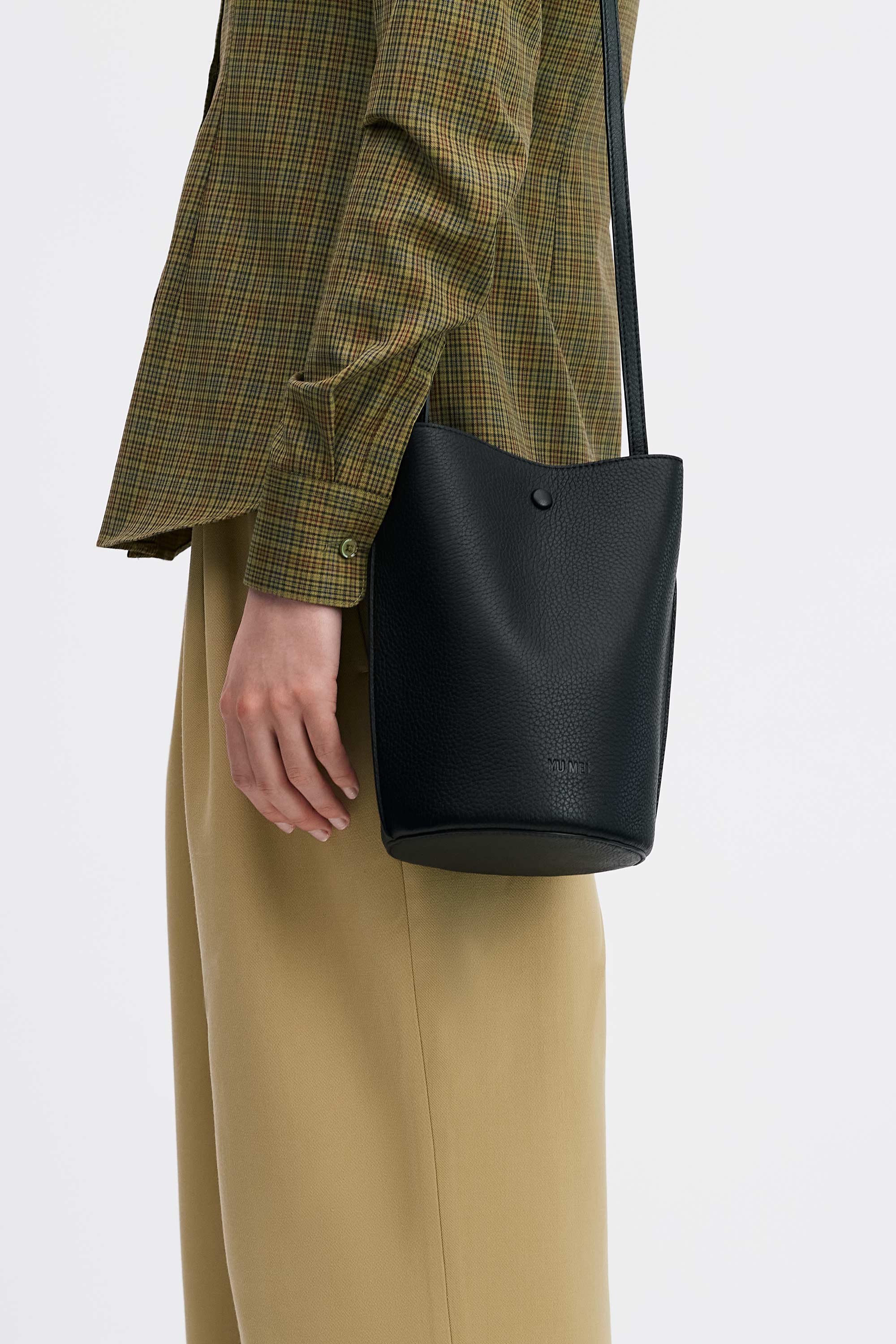 Phoebe Bucket in Black Deer Nappa worn on shoulder on model wearing check shirt and tan pants