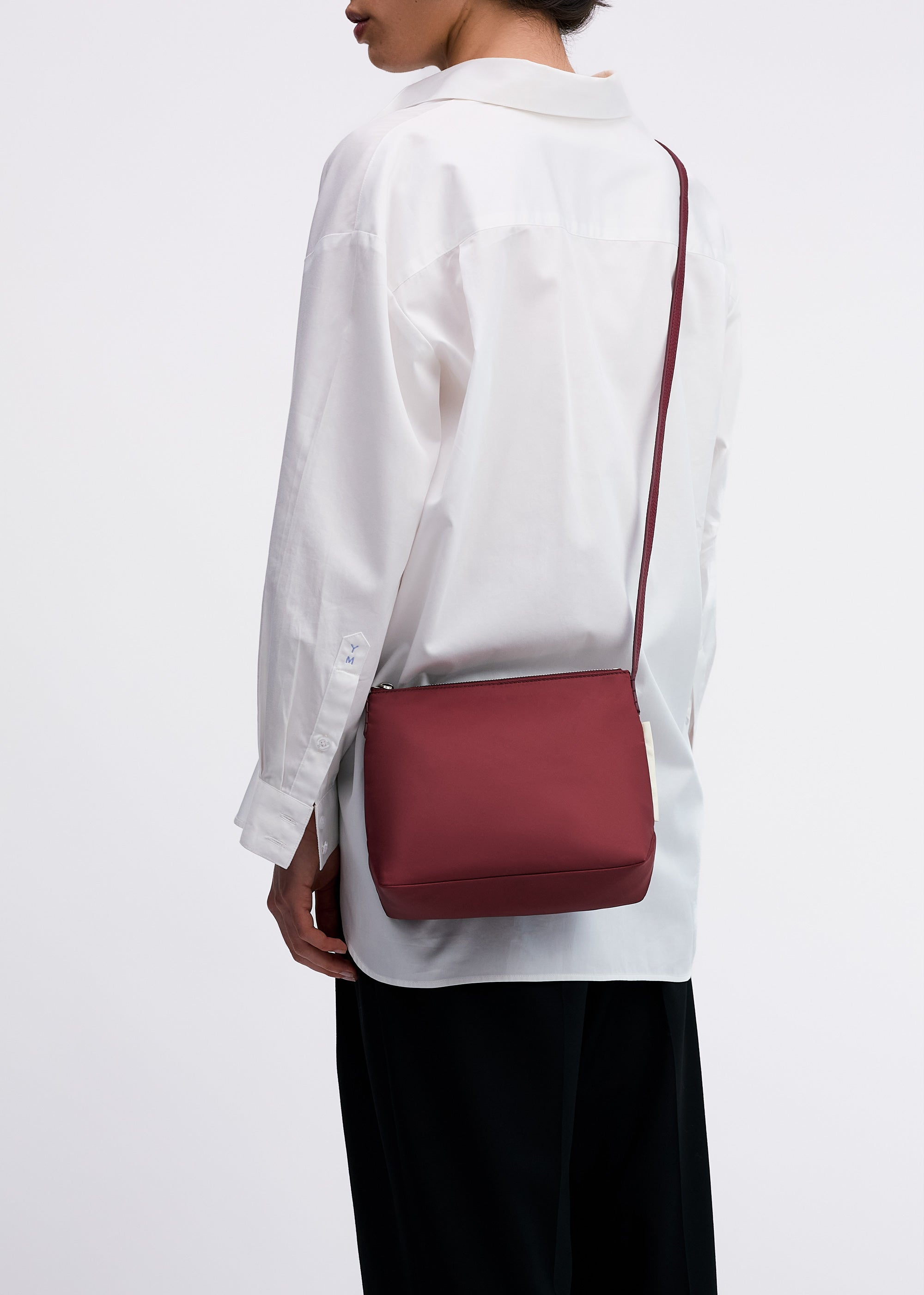 Yu Mei Small UTILITY Braidy in Pomegranate nylon worn crossbody on model wearing white shirt and black trousers