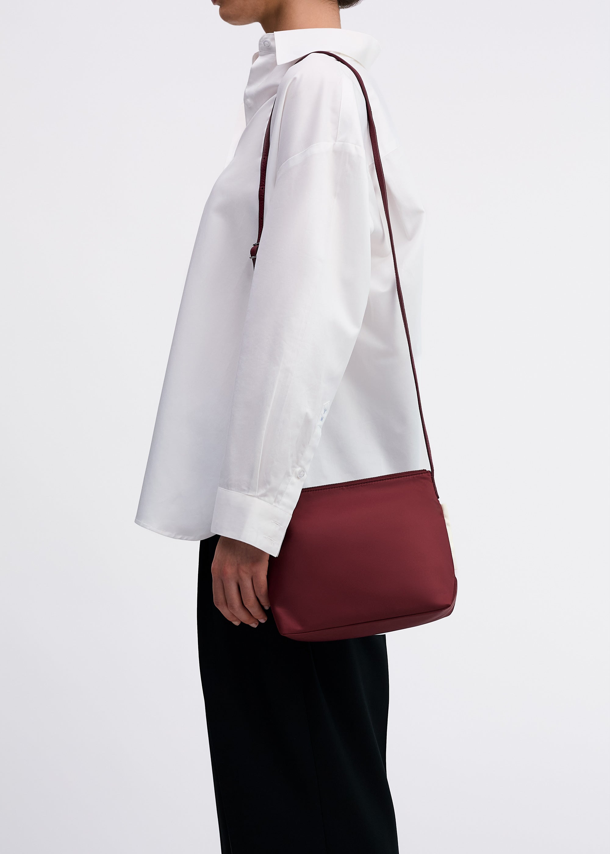 Yu Mei Small UTILITY Braidy in Pomegranate nylon worn on shoulder of model wearing white shirt and black trousers