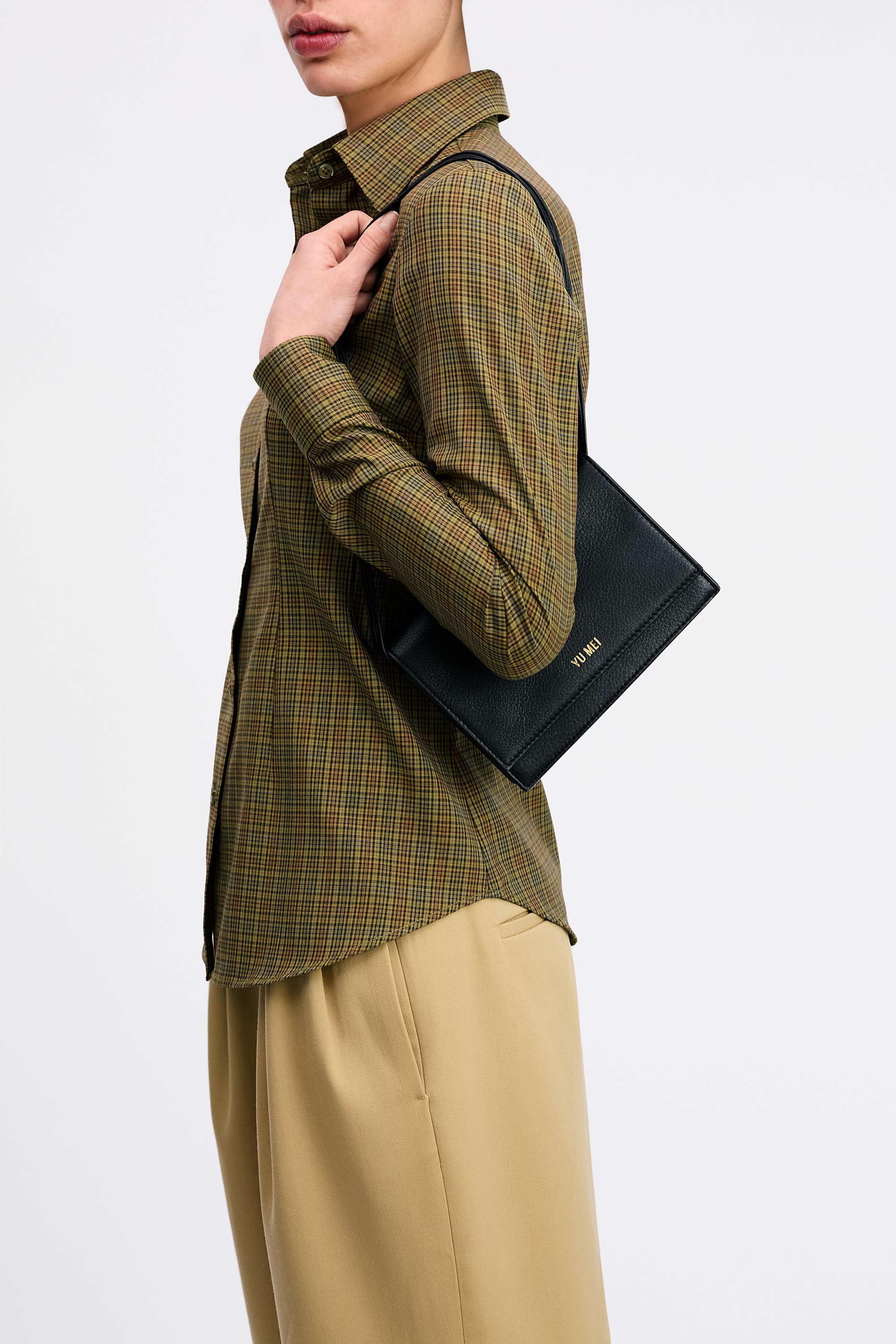 Suki Multi-Strap Clutch in Black Deer Nappa showing  detachable shoulder strap on model wearing check shirt and tan pants