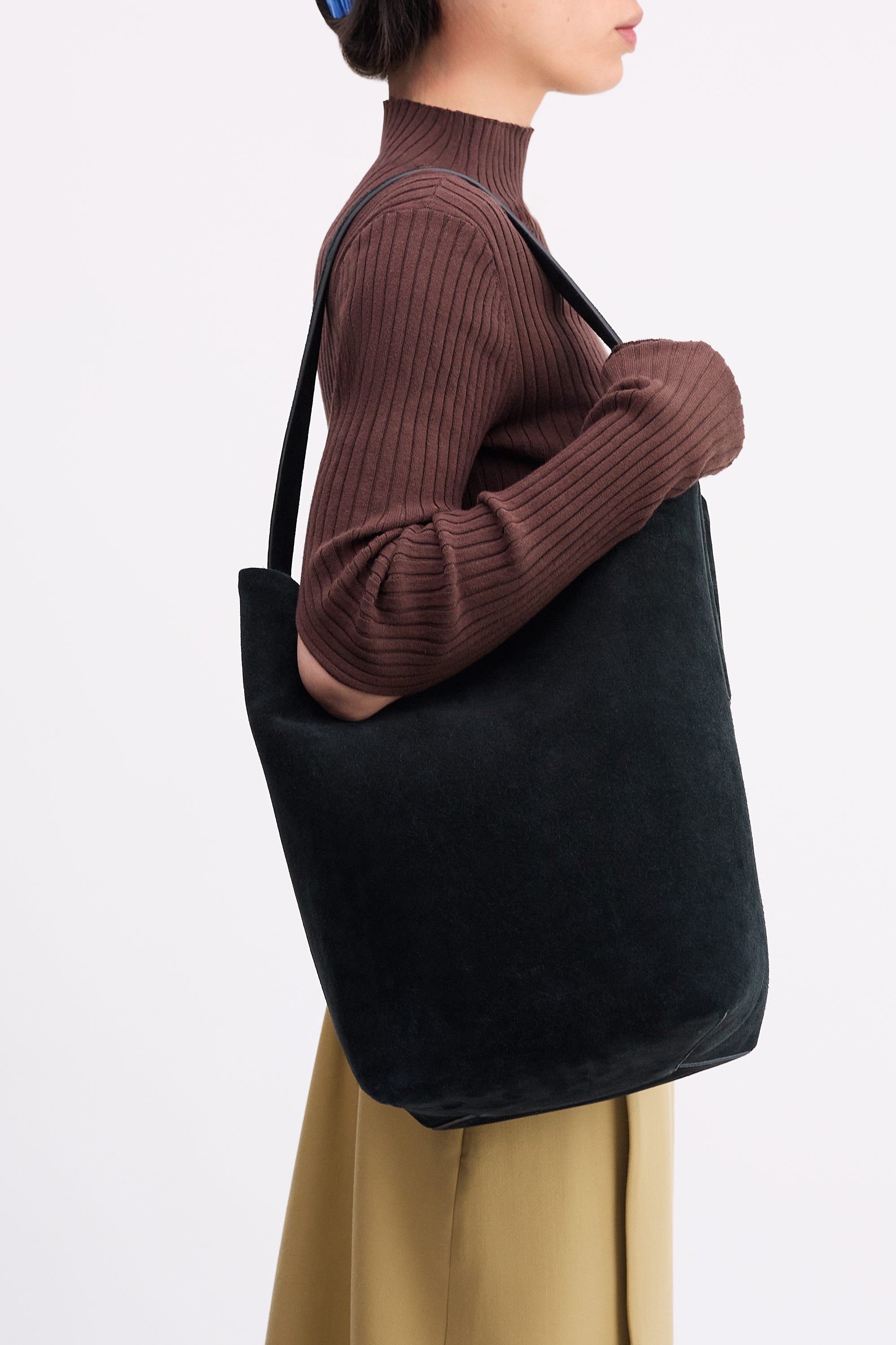 Teresa Tote in Black suede, worn on shoulder of person wearing brown top and tan skirt