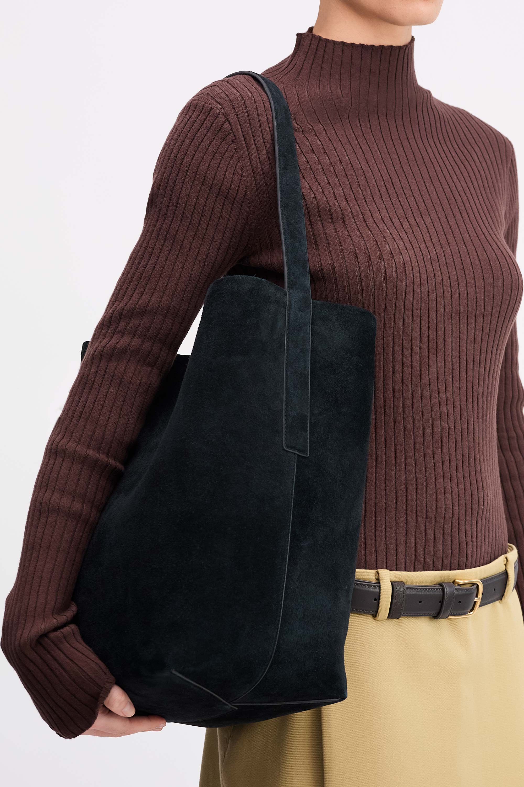 Teresa Tote in Black suede, worn on shoulder of person wearing brown top and tan skirt side view