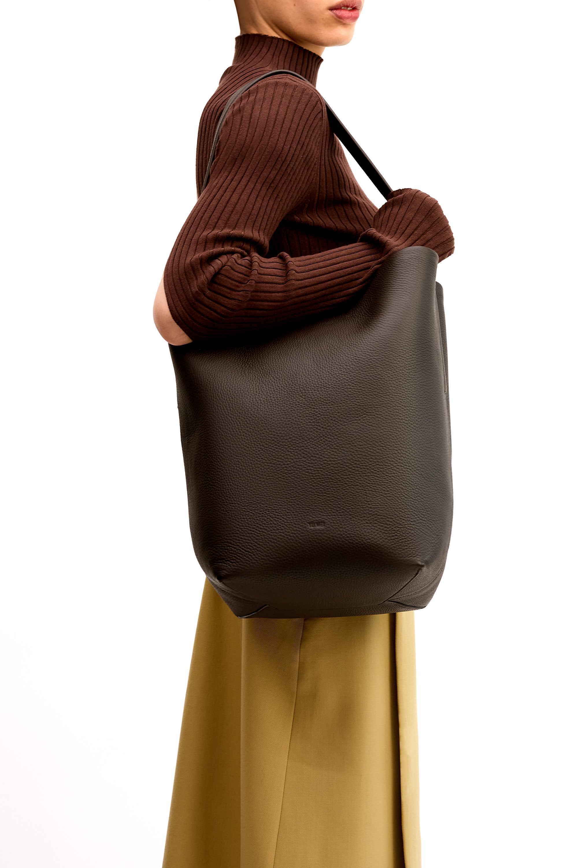 Model wearing the Teresa Tote in Molasses Deer Nappa on her shoulder wearing brown top and tan skirt