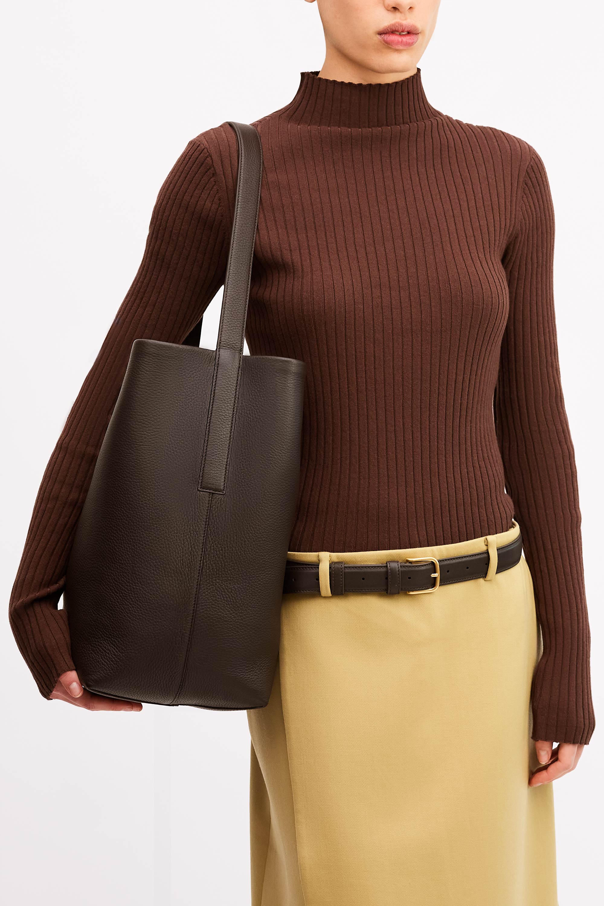 Model wearing the Teresa Tote in Molasses Deer Nappa on her shoulder wearing brown top and tan skirt