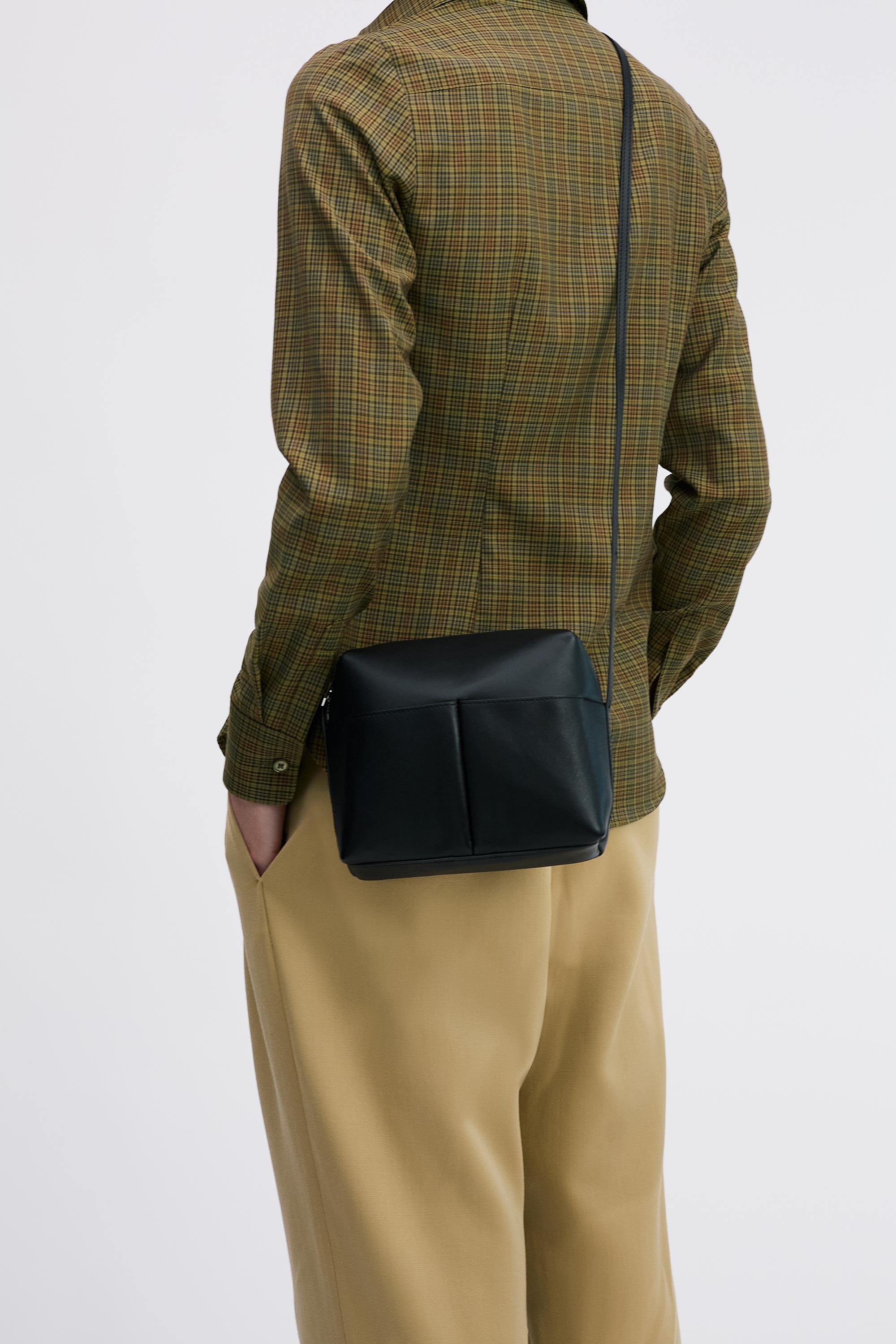 Kaye Bag in Black Lambskin, worn cross-body by model with check shirt and tan pants