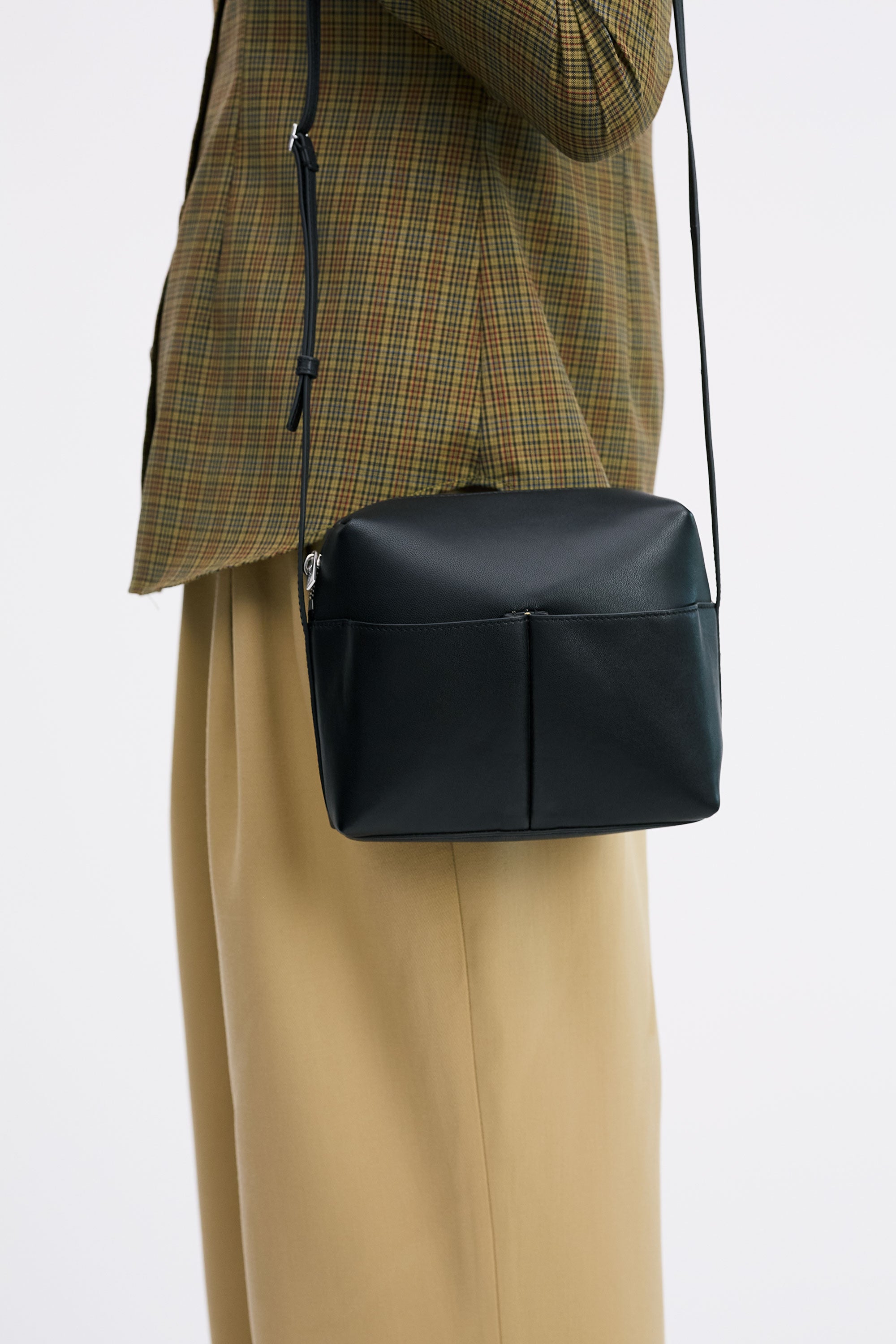 Kaye Bag in Black Lambskin, worn on shoulders by model with check shirt and tan pants