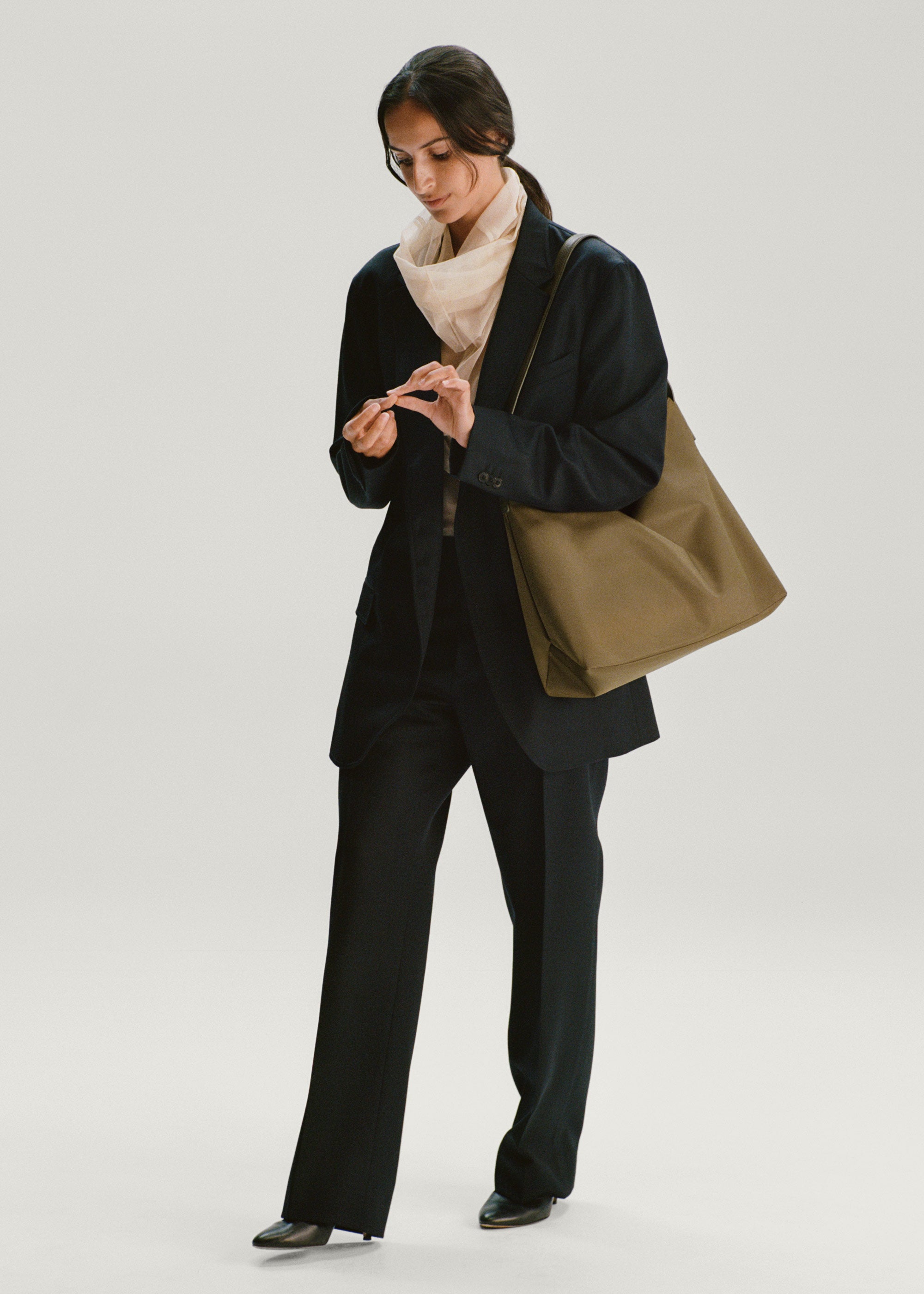 Model wearing the Medium UTILITY Braidy Bag in Fir Green nylon on shoulder wearing black suit